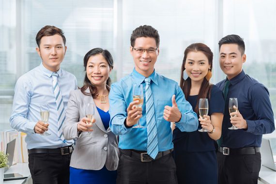 Cheerful-Asian-business-team-holding-champagne-glasses