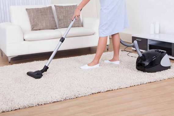 Maid Cleaning Carpet With Vacuum Cleaner