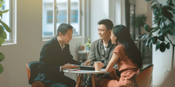 Asian couple discussing with property agent on their first home purchase