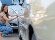 Asian woman inspecting the damage after a car accident
