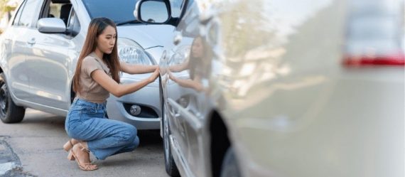 Asian woman inspecting the damage after a car accident Asian woman inspecting the damage after a car accident