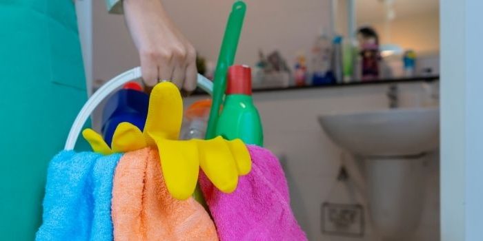 Domestic helper holding a bucket of cleaning tools and liquids