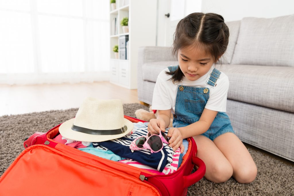 a girl leaning, packing her own suitcases, ready for travel, as she completed her travel essentials list