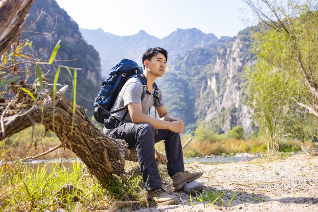 a male hiker taking a rest on a log