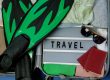 an open suitcase with water sports equipment, beach clothes, sunglasses, and a board that says TRAVEL